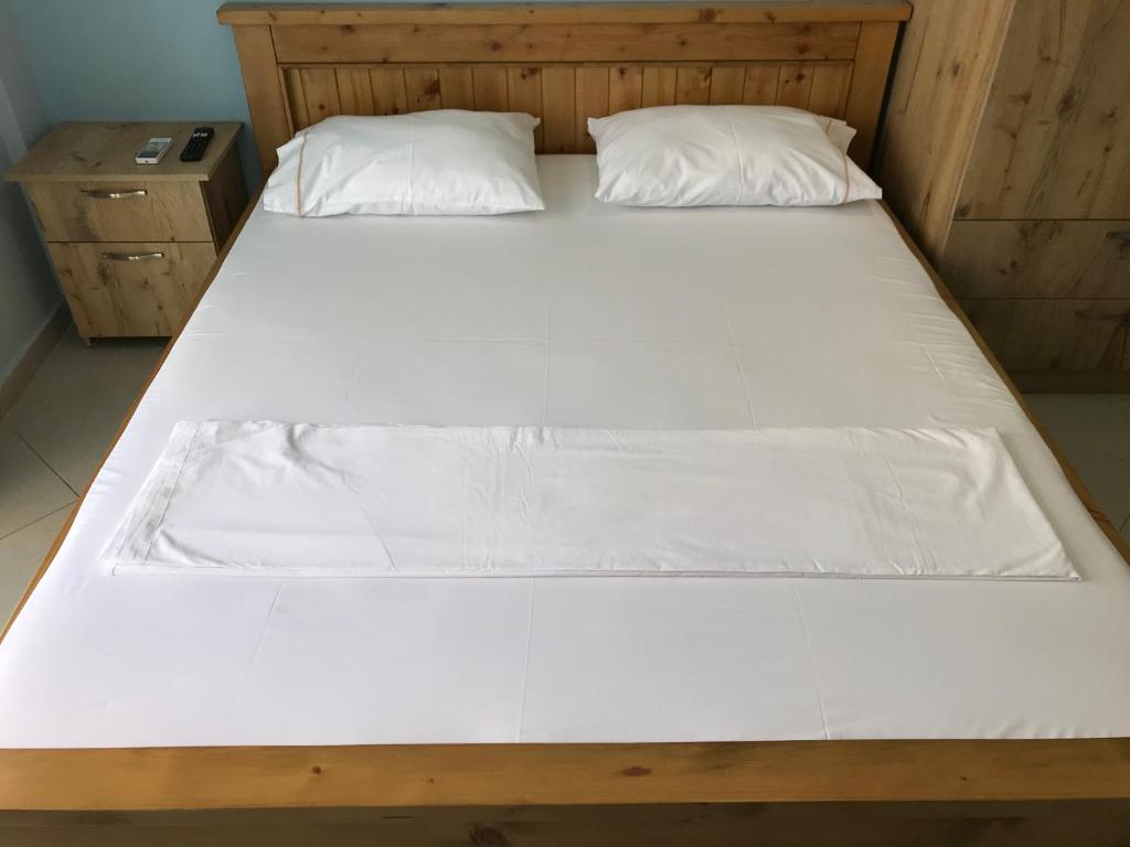 a large bed with white sheets and pillows on it at Vila Bedro in Sarandë