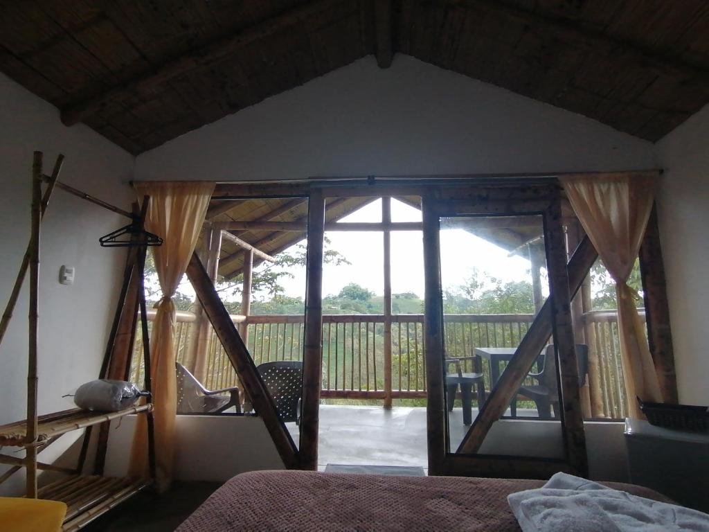 a bedroom with a large glass door with a balcony at Alojamiento rural finca la bendición in Filandia