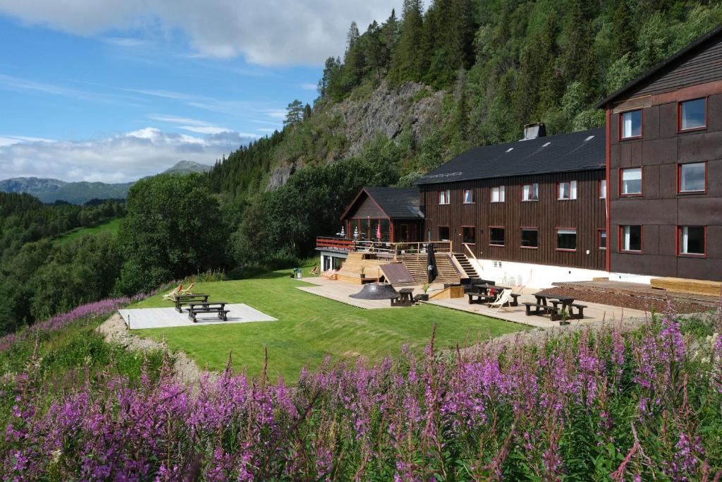 a building with a field of grass and purple flowers at Austbø Hotell in Rauland
