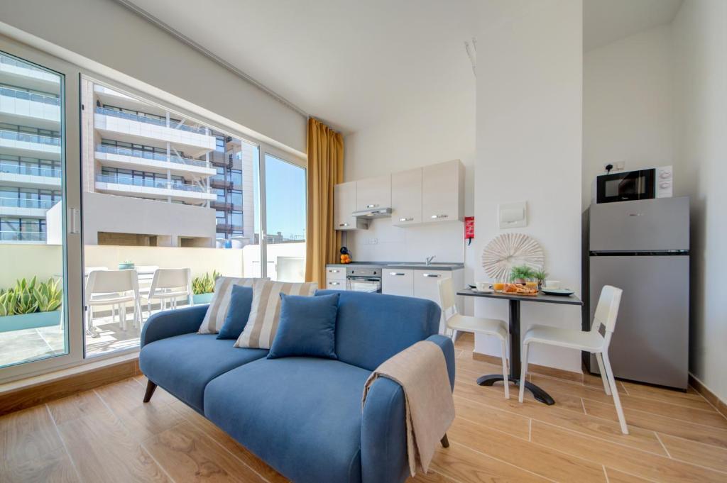 uma sala de estar com um sofá azul e uma cozinha em Marina Suites & apartments - Self catering - by Tritoni hotels em Il-Gżira