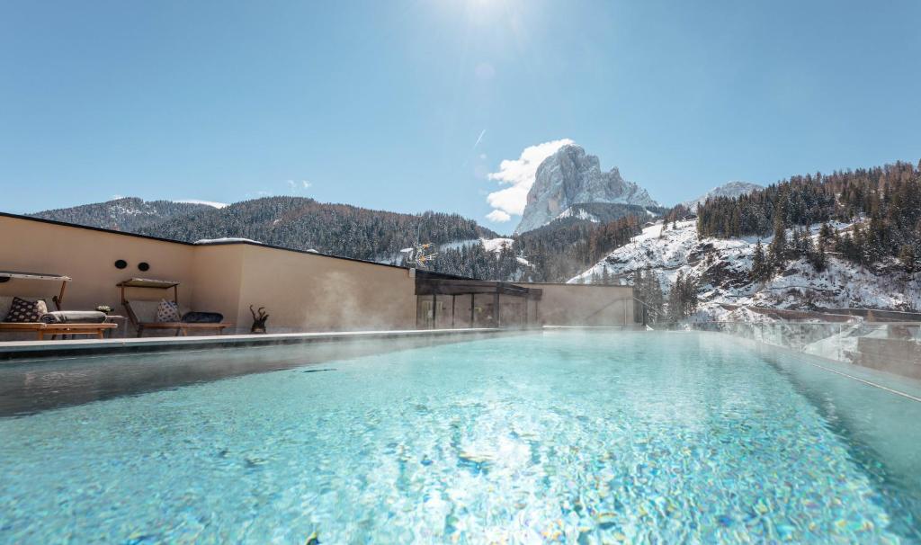 a swimming pool with a mountain in the background at Hotel Touring Dolomites in Santa Cristina in Val Gardena