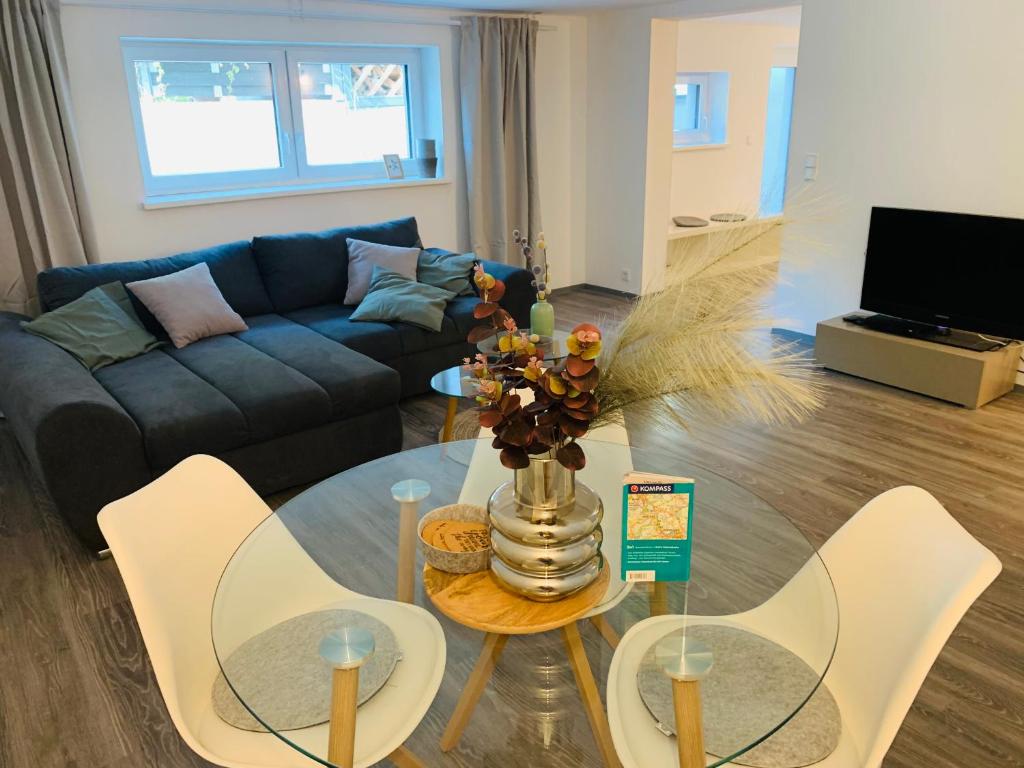 uma sala de estar com um sofá, uma mesa e cadeiras em Schickes Apartment mit direkter Waldrandlage em Geisenheim