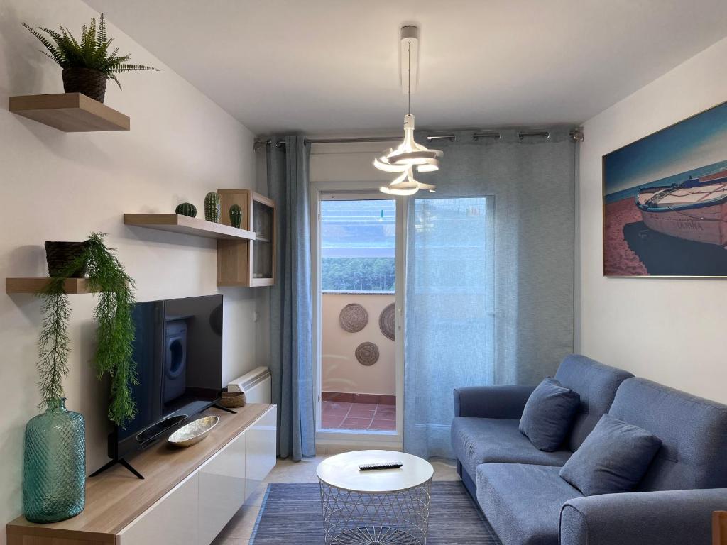 ein Wohnzimmer mit einem blauen Sofa und einem Fernseher in der Unterkunft Ático en Boiro La Niña, a 50m. Playa Jardín. in Boiro