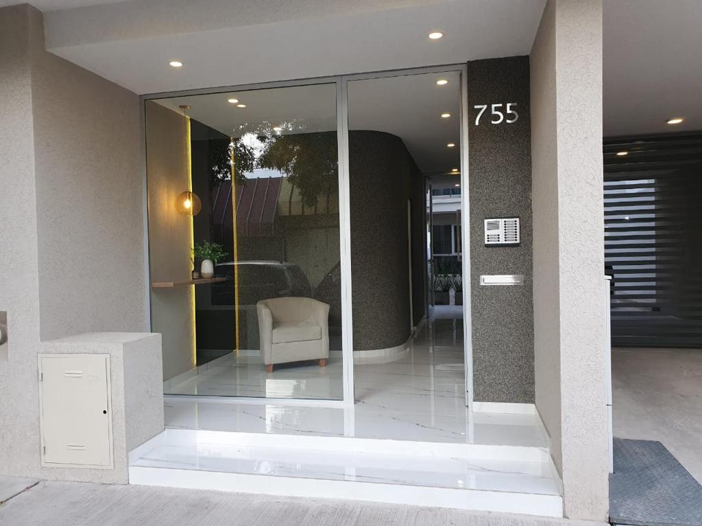 a glass entrance to a building with a chair at Departamento Alva in Bahía Blanca