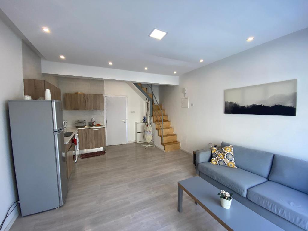 uma sala de estar com um sofá azul e uma cozinha em 1-bedroom duplex 100m by the sea em Limassol