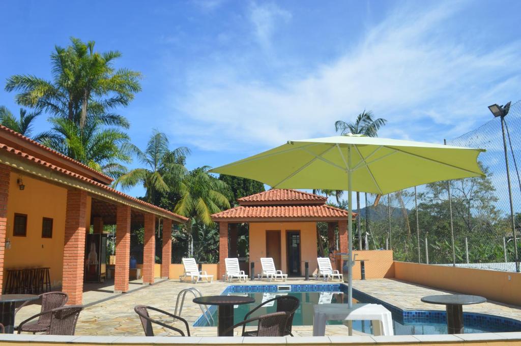 eine Terrasse mit einem Tisch und einem Sonnenschirm neben einem Pool in der Unterkunft Sítio Oliveira in Itariri