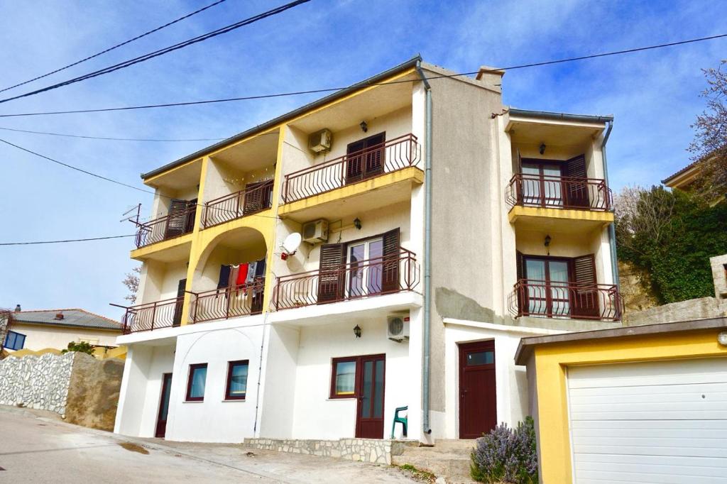 un edificio bianco con balconi e un garage di Apartments with a parking space Senj - 16747 a Senj