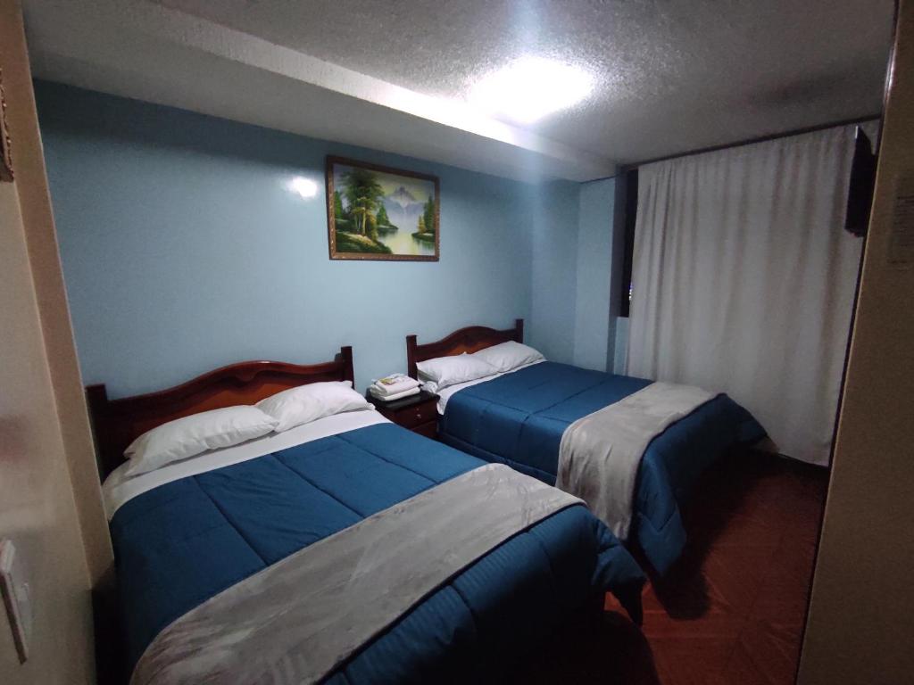 Duas camas num quarto com paredes azuis em Hostal Buenaventura Ibarra em Ibarra