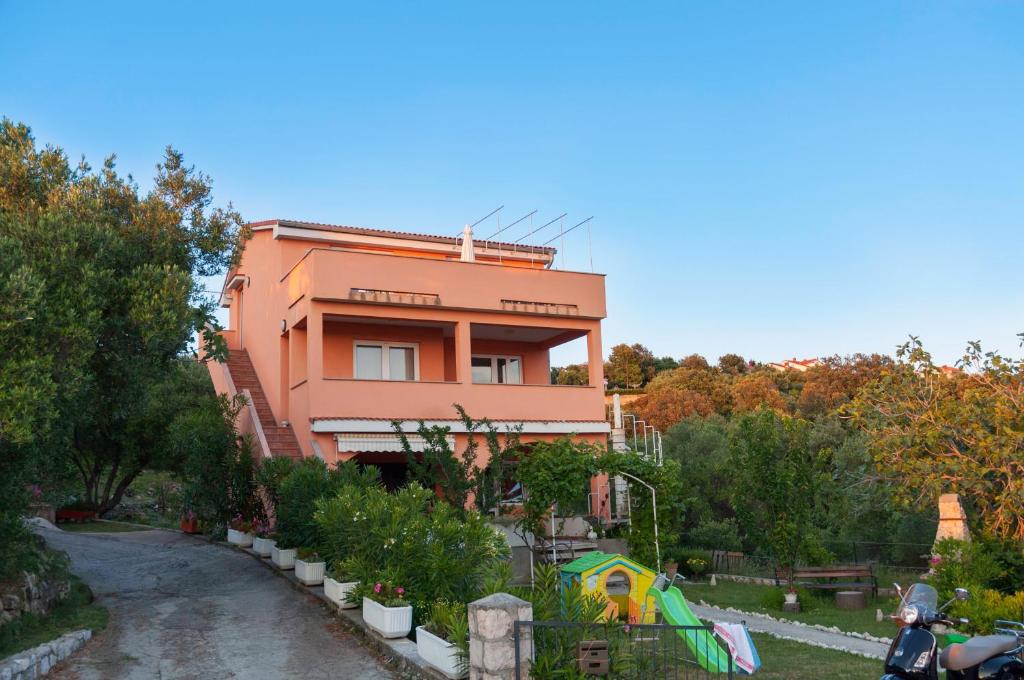 a tall orange building with trees and a street at Apartments by the sea Supetarska Draga - Gonar, Rab - 16738 in Rab