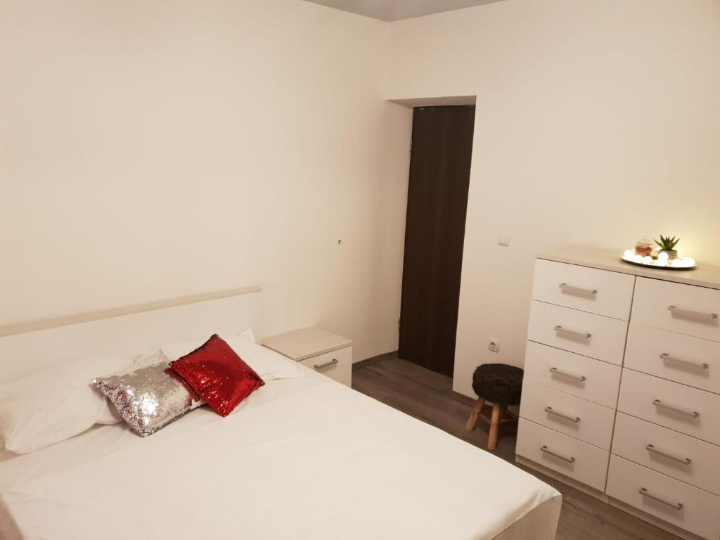 una camera da letto con un letto bianco con un cuscino rosso di Apartments by the sea Podstrana, Split - 16793 a Podstrana
