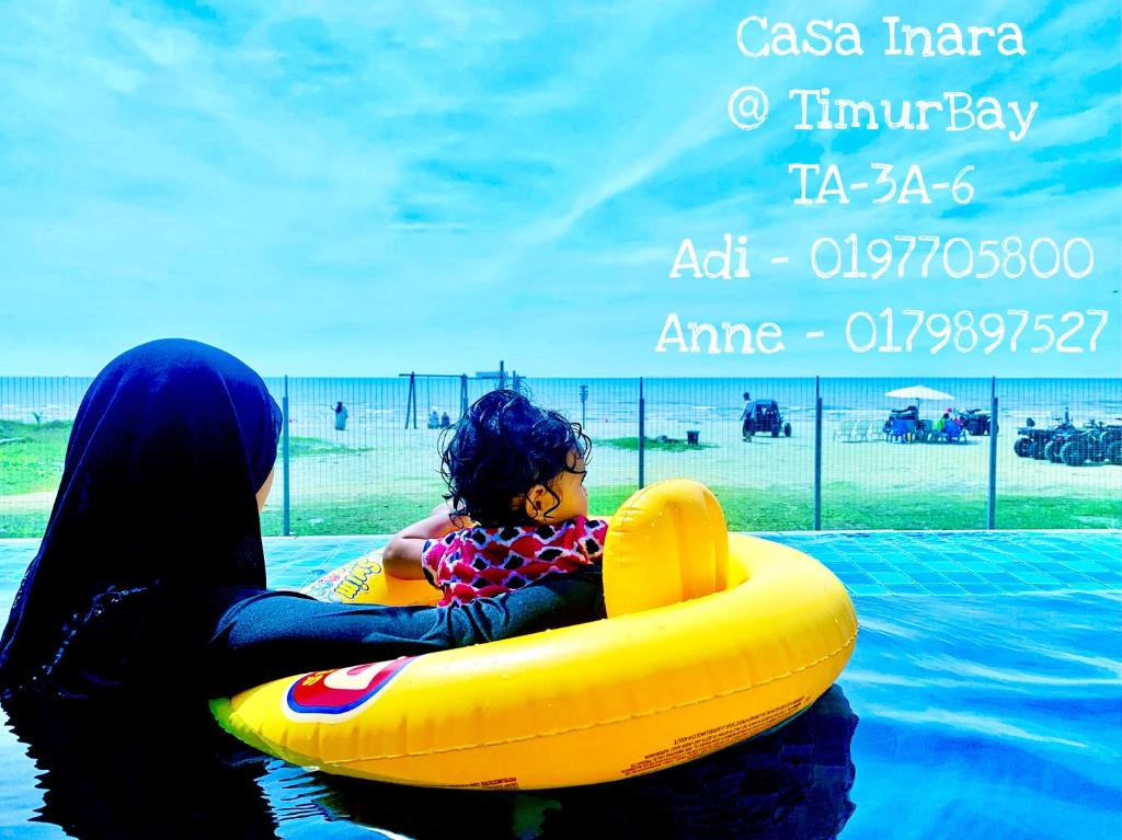 クアンタンにあるTimurBay Seafront Residence at Casa Inaraの水筏に子供を抱いた女