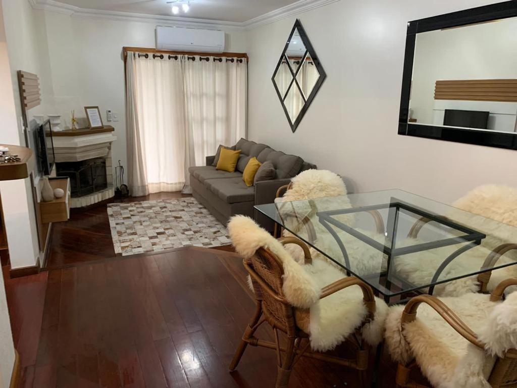 a living room with a glass table and chairs at Apto próximo aos pontos turísticos e restaurantes in Gramado