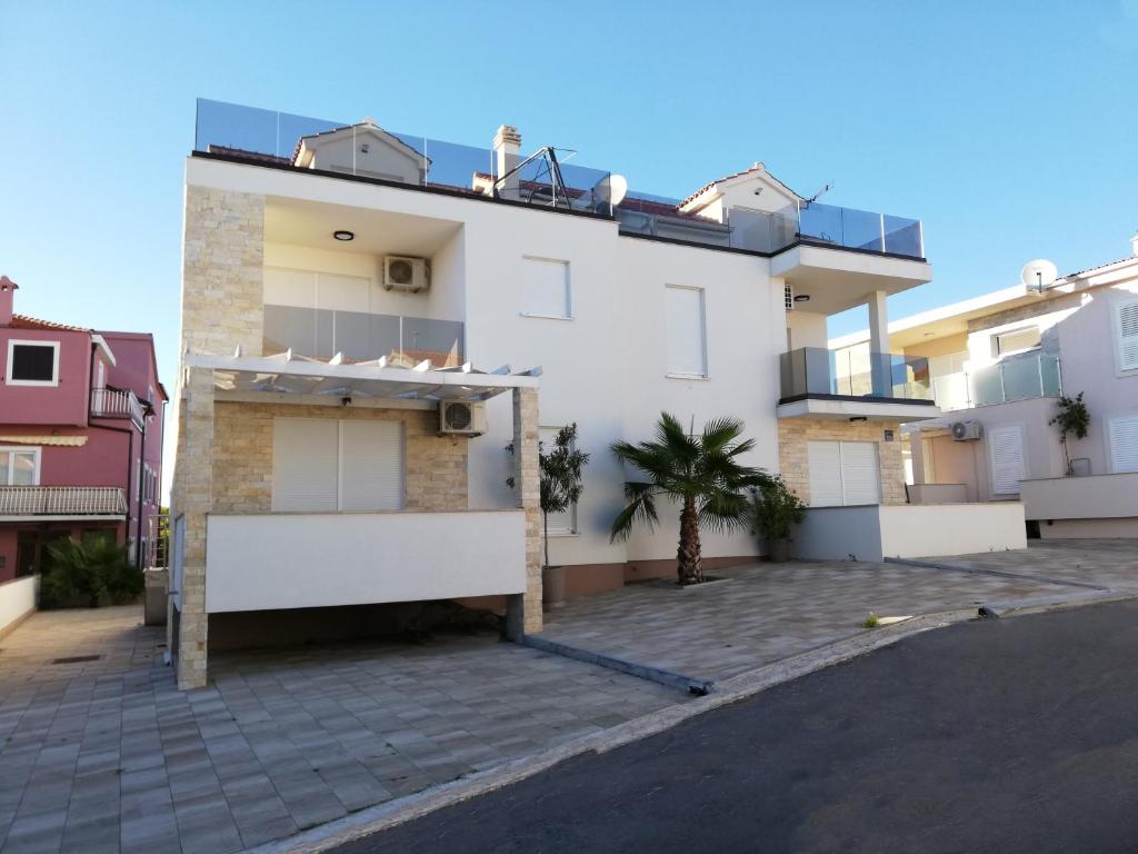 a white apartment building with a parking lot at Apartment Tribunj 16884b in Tribunj