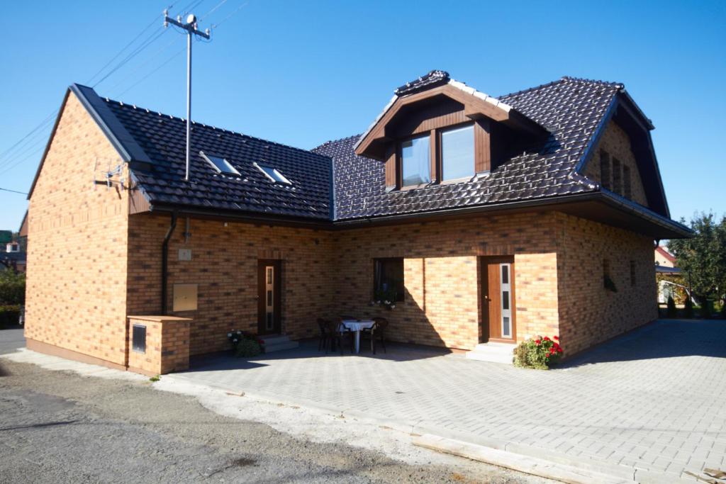 a brick house with a black roof and a patio at U Haryho in Dolní Bečva