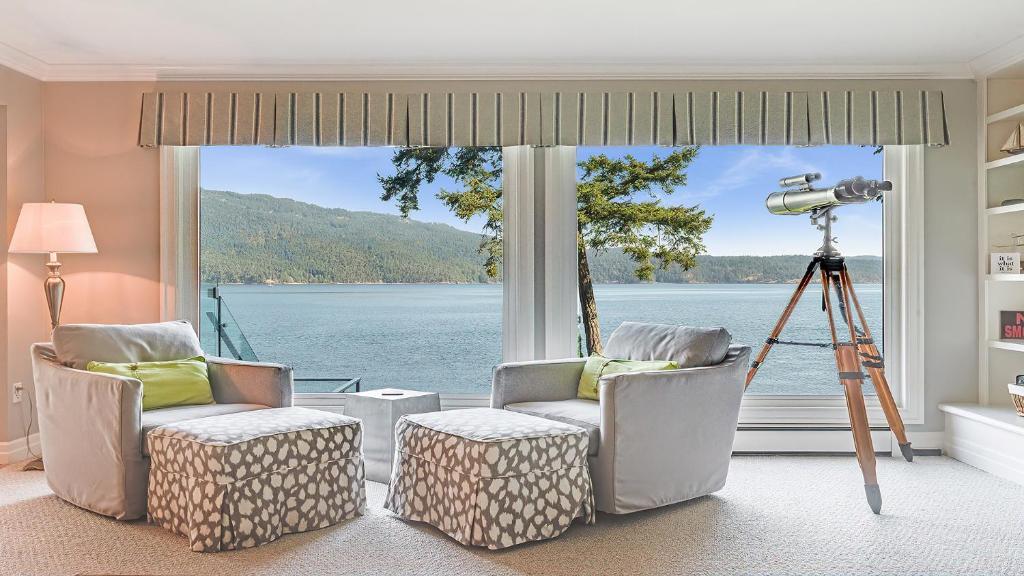 a room with two chairs and a camera in front of a window at Deep Cove Retreat on the Ocean in North Saanich