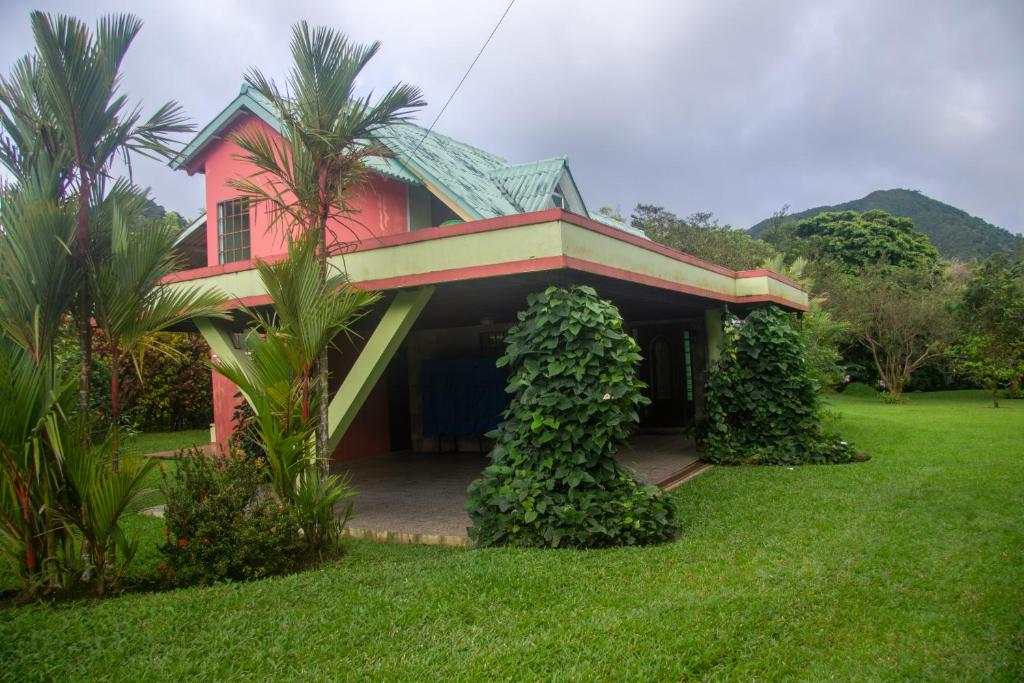 a red house with a green roof on a yard at Residencia entera Valle de Anton, El Valle de Lily in El Valle de Antón