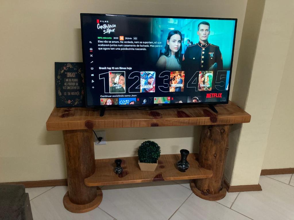 a tv on a wooden stand with a tv screen at Apartamento Cambara com churrasqueira e uma ampla sacada in Cambara do Sul