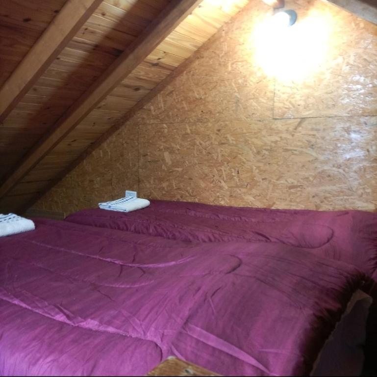 een paars bed op een zolder met een bakstenen muur bij CABAÑA LOS MORROS in Ushuaia
