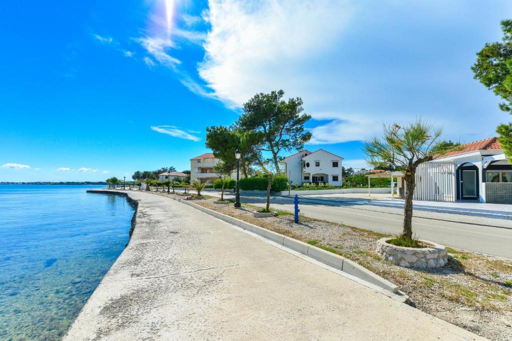 chodnik obok zbiornika wodnego z domami w obiekcie Apartments by the sea Vir - 18590 w mieście Vir