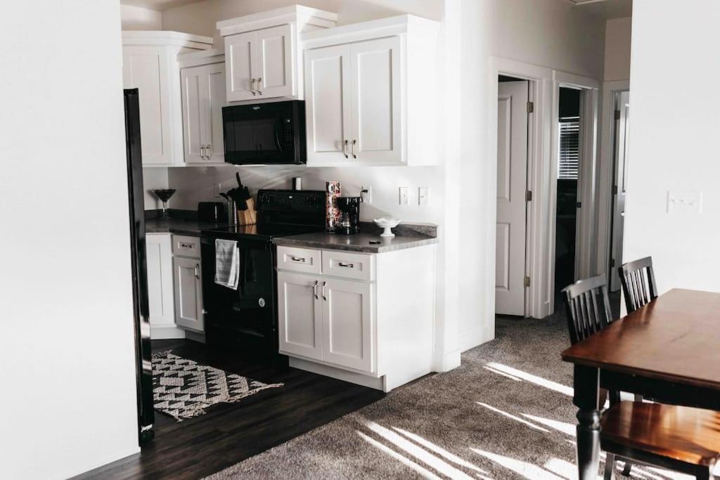 uma cozinha com armários brancos e um balcão preto em NEW CONDO Cache Valley 3BR 2BA - Sleeps 7 em Logan
