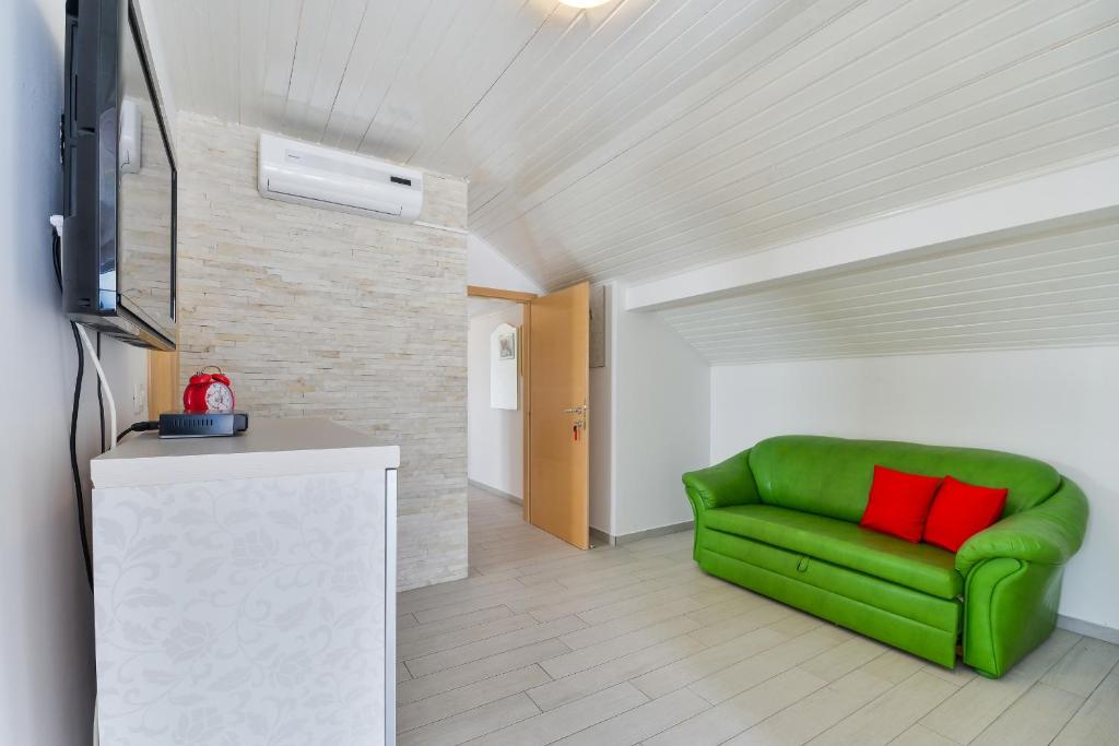 ein Wohnzimmer mit einem grünen Sofa und einem TV in der Unterkunft Apartments with a parking space Vir - 18581 in Vir