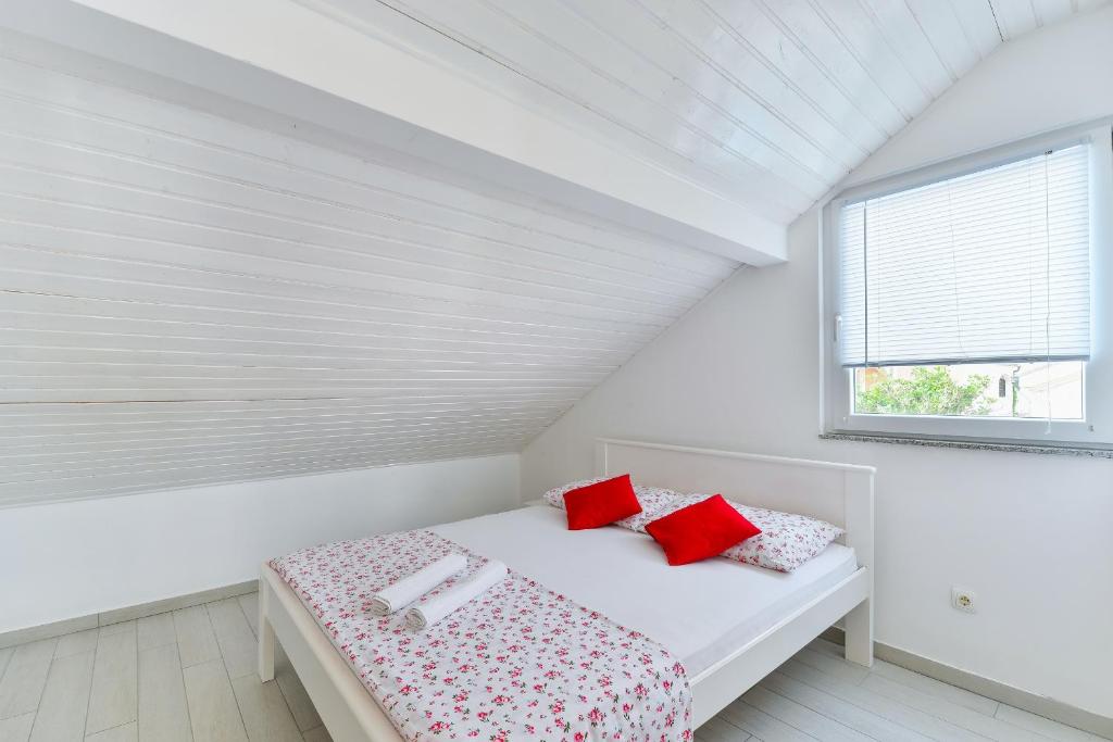 ein weißes Schlafzimmer mit einem Bett mit roten Kissen in der Unterkunft Apartments with a parking space Vir - 18581 in Vir