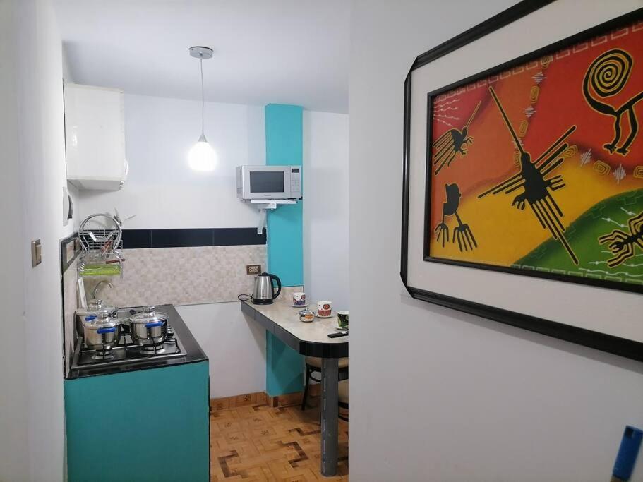 una pequeña cocina con una mesa y una pintura en la pared en Departamento Smart- Chiclayo B2 en Chiclayo