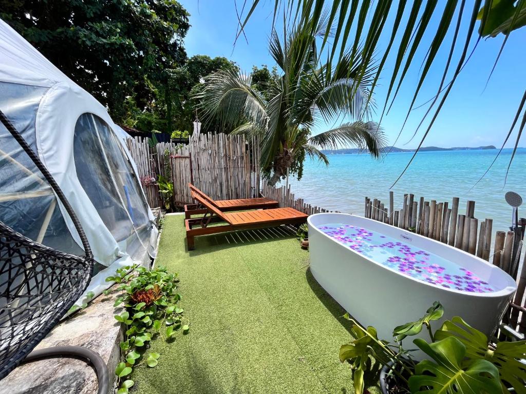 a bath tub sitting on the grass next to the ocean at Phuket Signature Glamping in Rawai Beach