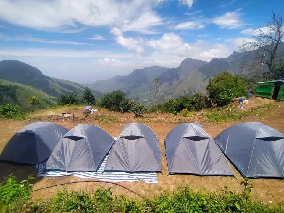 ムンナルにあるMunnar Tent Campingの山を背景にした野原四棟