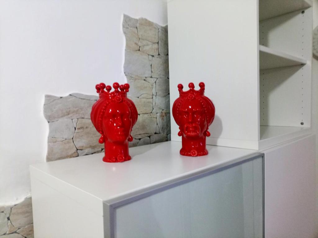 dos jarrones rojos sentados en la parte superior de un estante en La casa di Anna, en Patti