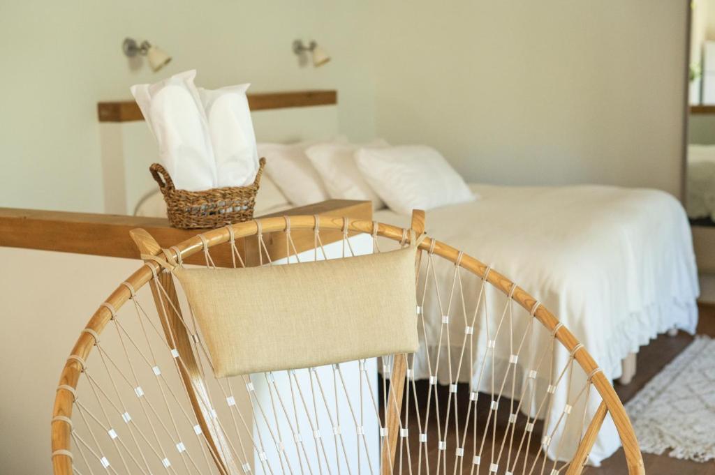 a bedroom with a bed with white sheets and a basket at Hanahala Beramot - Boutique Suites in Moshav Ramot