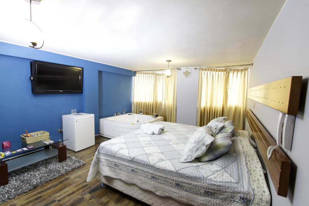 ein Schlafzimmer mit einem Bett, einer Badewanne und einem TV in der Unterkunft Padama in Lima
