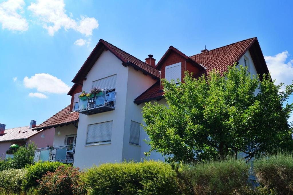 a white house with a balcony and a tree at Ferienwohnung Hyggelig in Waldershof