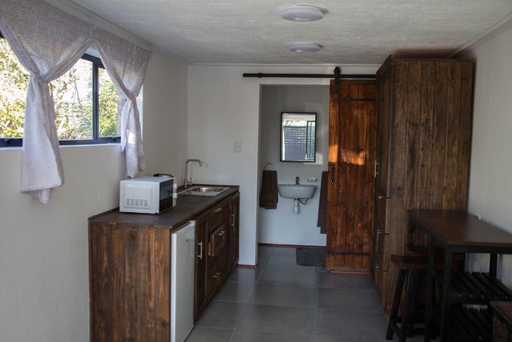 a kitchen with wooden cabinets and a sink and a bathroom at Peaceful 1-bedroom flatlet, 10 min from the beach in Cape Town