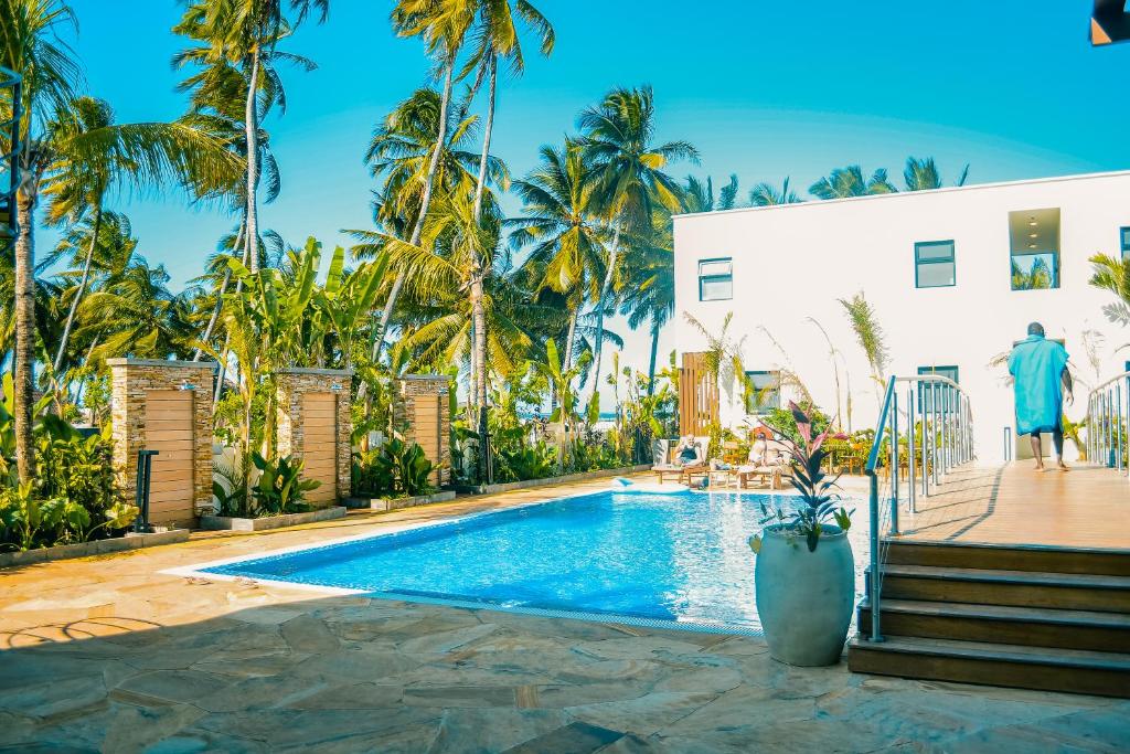 a swimming pool in front of a white building with palm trees at TOA Hotel & Spa Zanzibar in Pongwe