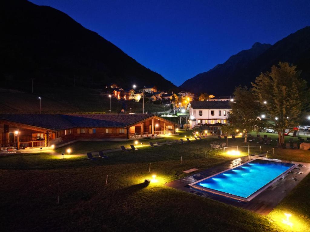 a resort with a swimming pool at night at Hostellerie Le Lievre Amoureux in Valpelline