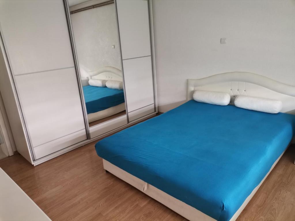 a small bedroom with a blue bed and mirrors at Garden- pool apartman 