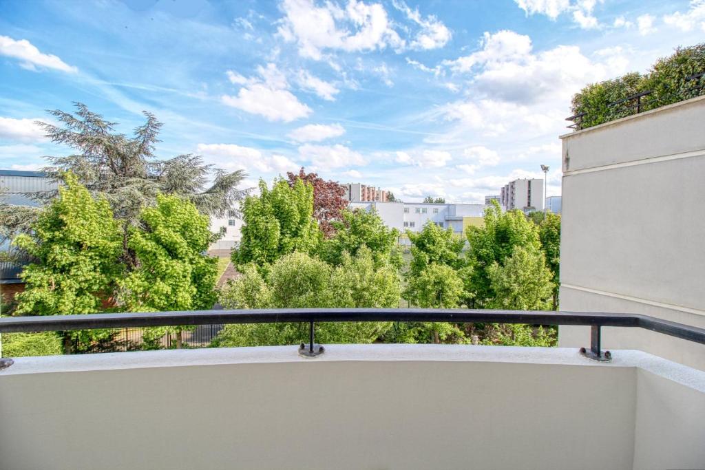 einen Balkon mit Blick auf Bäume und Gebäude in der Unterkunft Appartement Proche U Arena et La Défense in Nanterre