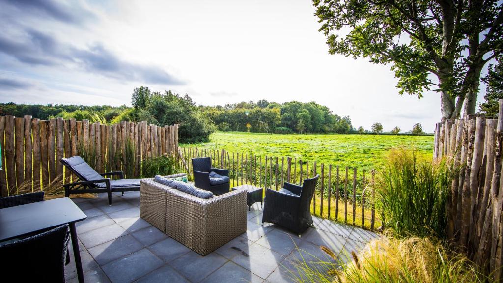 a patio with chairs and a fence and a field at Guesthouse Scherp in Middelburg