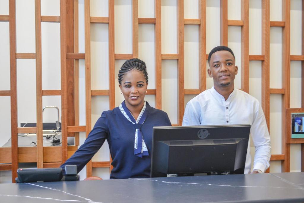 a man and a woman standing at a table with a laptop at TOA Hotel & Spa Zanzibar in Pongwe