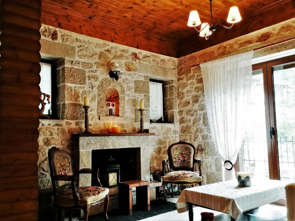 een stenen kamer met een open haard en een tafel en stoelen bij Stonehouse dome Lagadia in Lagadia