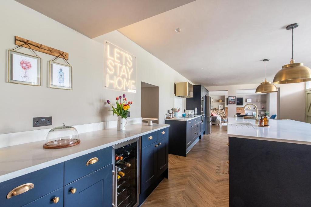uma grande cozinha com armários azuis e bancadas brancas em Immaculate 6 Bed House - Unique Cellar Bar- Airbnb em Warminster