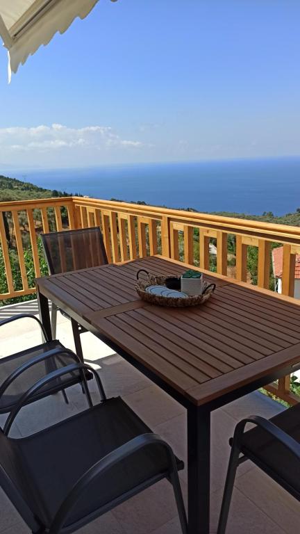 a wooden table and chairs on a deck with the ocean at Sun Meets Sea in Athanion