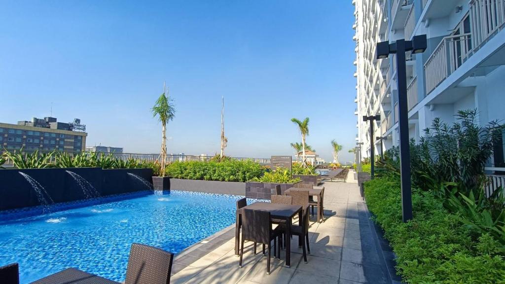 patio ze stołem i krzesłami przy basenie w obiekcie SMDC Coast Residences near PICC World Trade Center MOA w mieście Manila