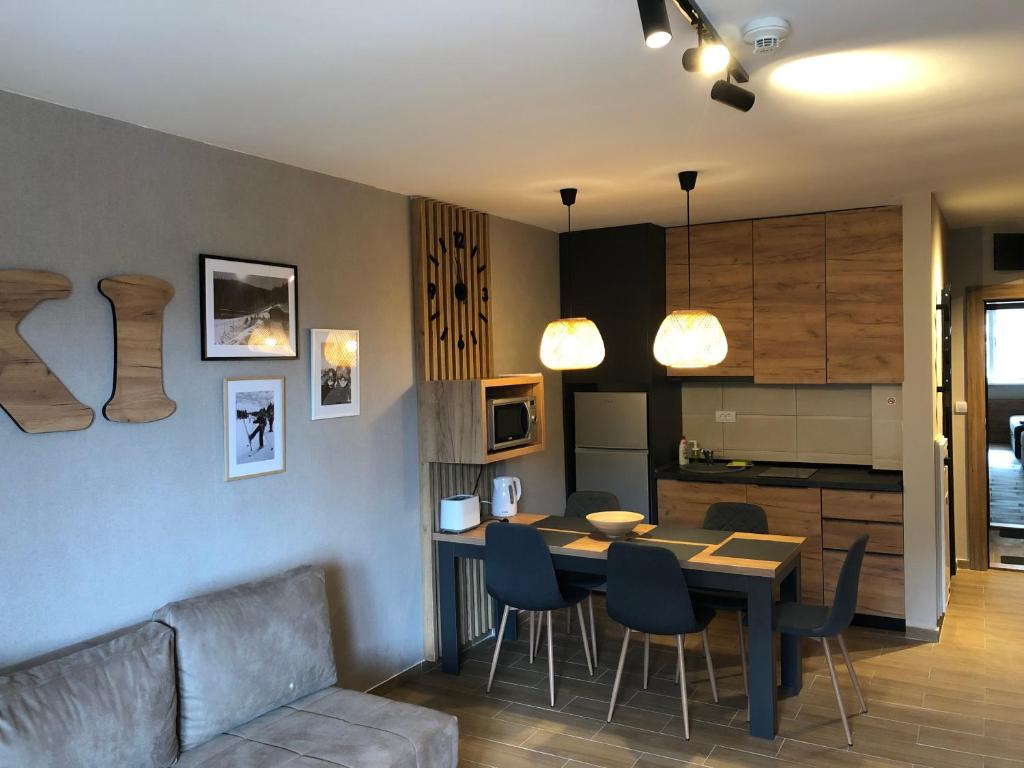 a living room and kitchen with a table and chairs at Apartmani A in Kopaonik