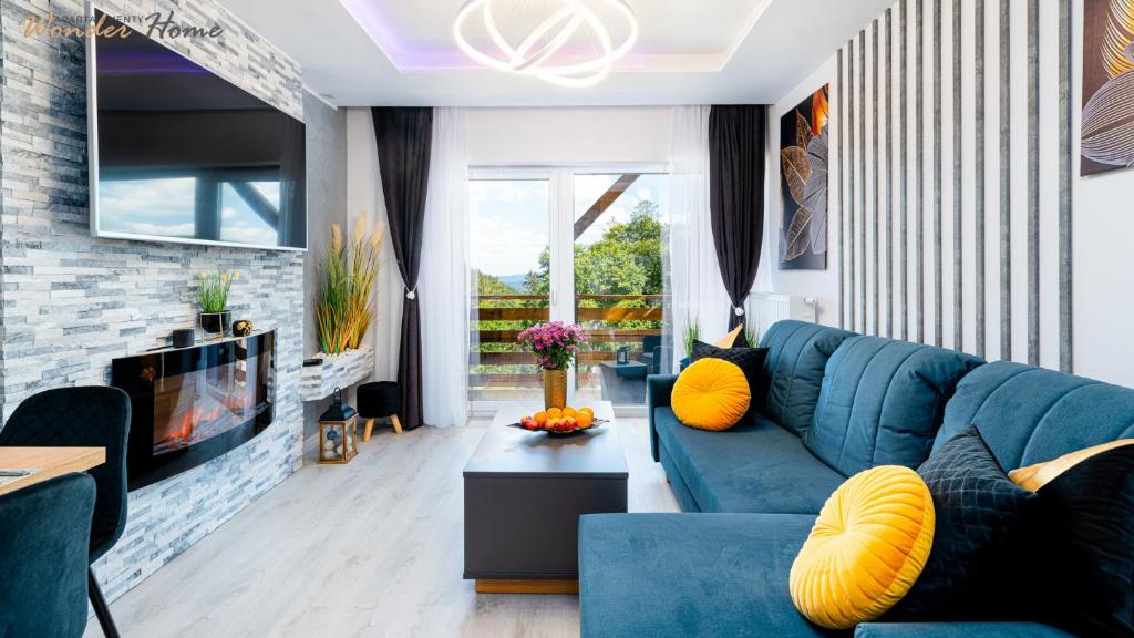 a living room with a blue couch and a fireplace at Wonder Home - Apartamenty Blisko Gór w zielonej części Karpacza - przy przy stoku i szlakach turystycznych in Karpacz