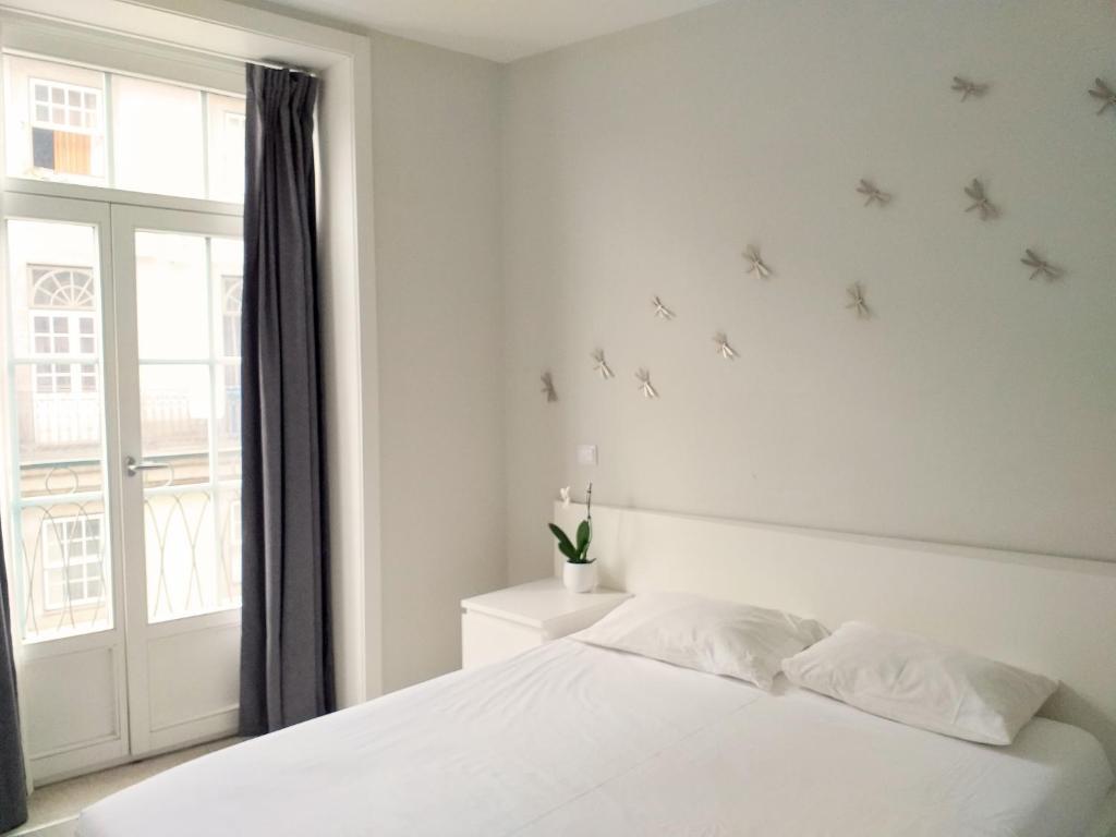 a white bedroom with a bed and a window at H2O Porto Ribeira in Porto
