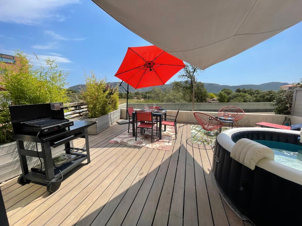 a deck with a pool and a piano and a table with chairs at Superbe appartement sur le port, jacuzzi, piscine in Porto-Vecchio