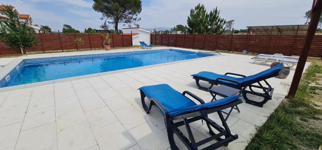 a swimming pool with two blue chairs next to it at Quinta Coração d'Ouro in Midões