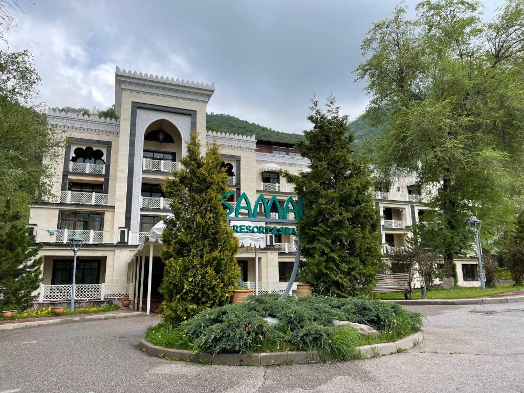 un grande edificio con alberi di fronte di Samal Resort & SPA a Almaty